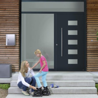 Mother fitting roller blades on small girl in front of home